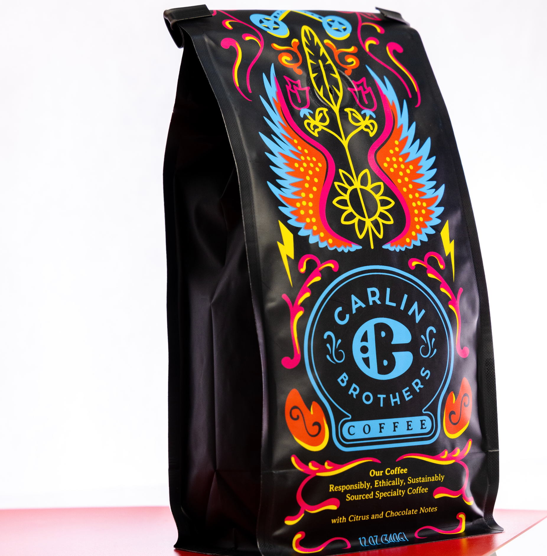 Colorful black Carlin Brother's Mercantile Coffee bag  12oz decaffeinated coffee. Responsibly, ethically, sustainably sourced specialty coffee with Citrus, Chocolate notes