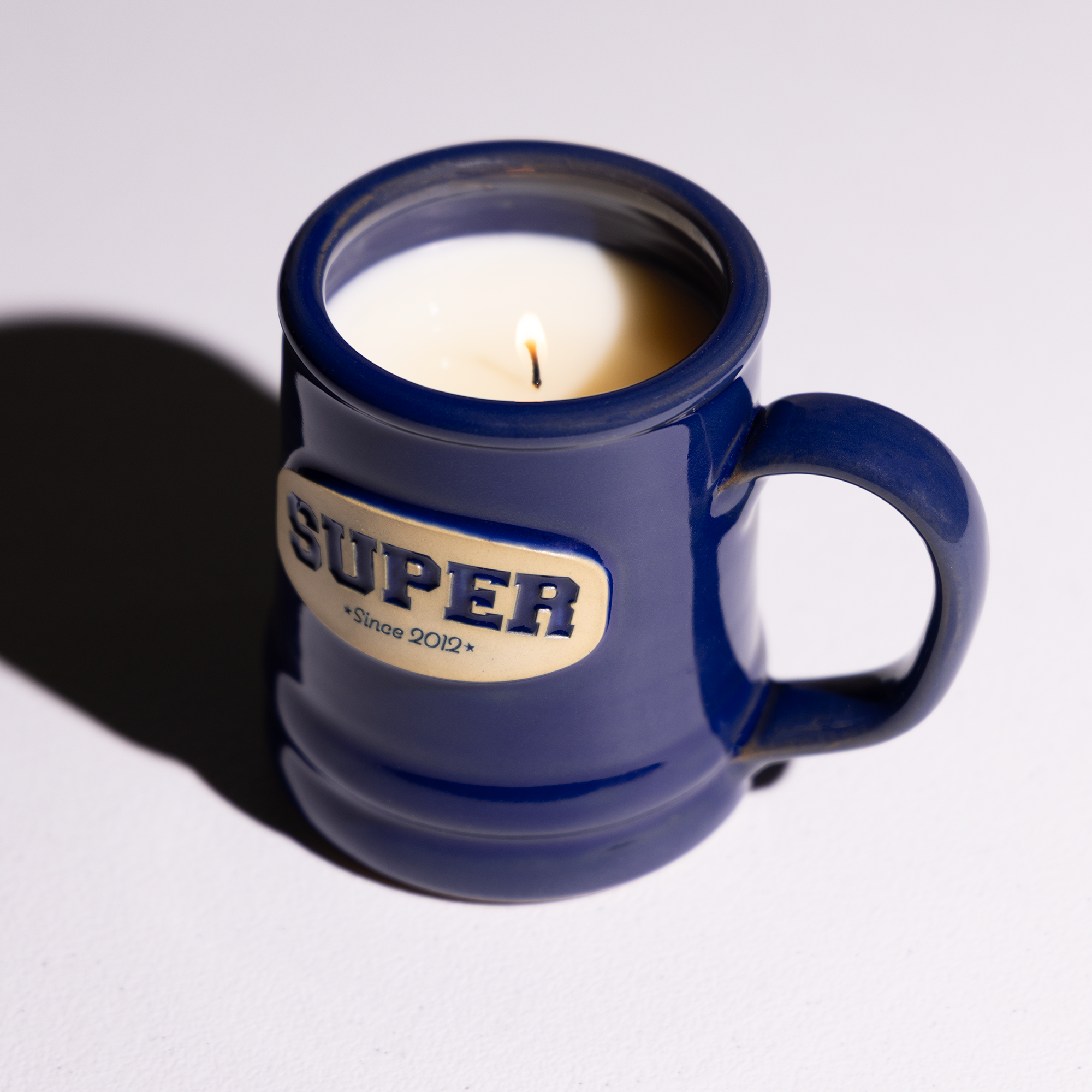 Blue mug with a candle inside on a white background
